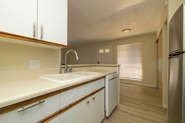 kitchen with light hardwood / wood-style floors, white cabinetry, sink, dishwasher, and a textured ceiling
