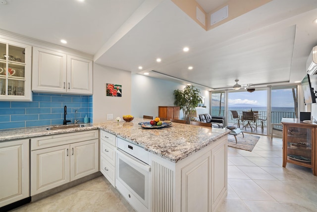 2430 S Kihei Rd Unit 411, Kihei, HI 96753 - kitchen with a sink, a peninsula, oven, tasteful backsplash, and light stone counters