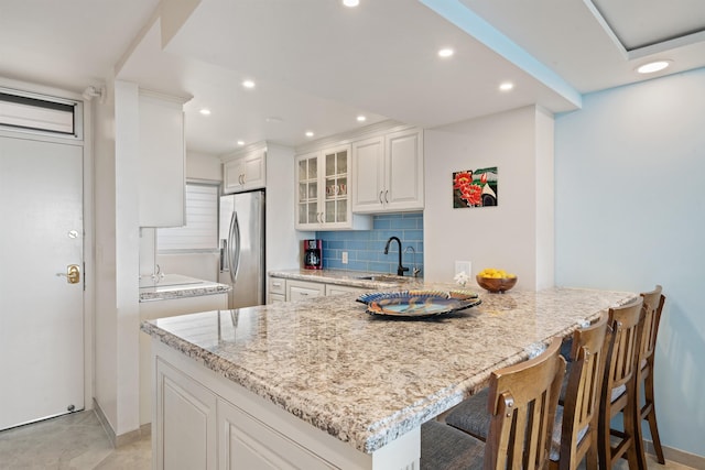 2430 S Kihei Rd Unit 411, Kihei, HI 96753 - kitchen featuring a sink, stainless steel refrigerator with ice dispenser, light stone counters, a peninsula, and decorative backsplash
