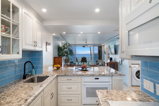 2430 S Kihei Rd Unit 411, Kihei, HI 96753 - kitchen featuring white appliances, a sink, washer / clothes dryer, a peninsula, and white cabinetry