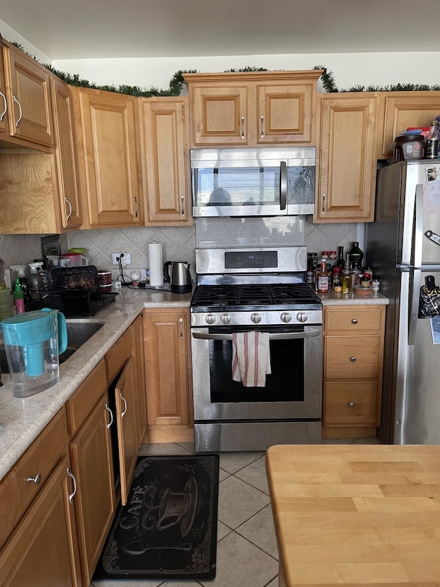 kitchen featuring backsplash, light tile patterned flooring, and stainless steel appliances