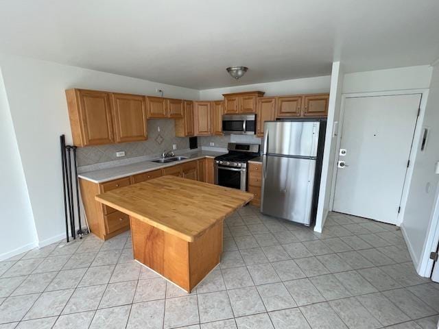 kitchen featuring backsplash, stainless steel appliances, sink, a kitchen island, and butcher block counters