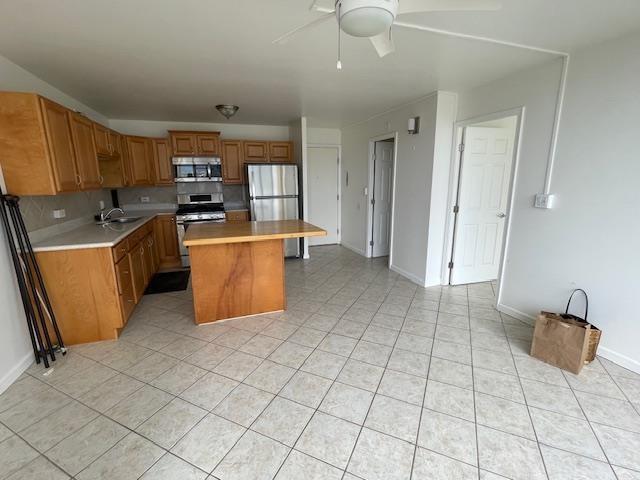 kitchen with a center island, ceiling fan, decorative backsplash, light tile patterned floors, and stainless steel appliances