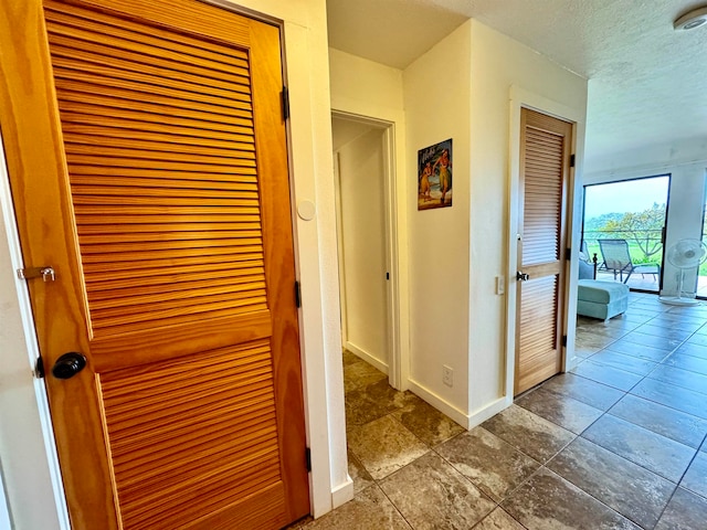 hallway featuring dark tile floors and a textured ceiling