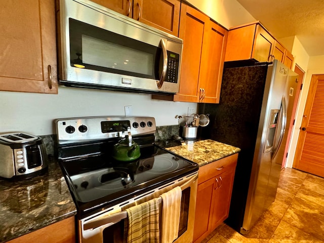 kitchen featuring light tile floors, dark stone counters, and stainless steel appliances