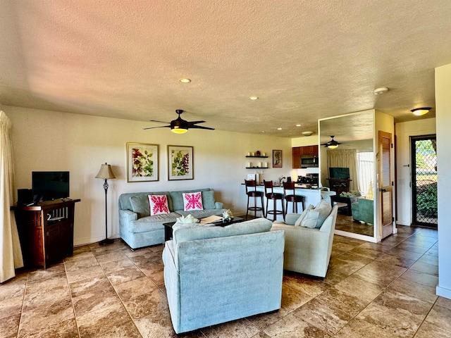 living room with light tile floors, ceiling fan, and a textured ceiling