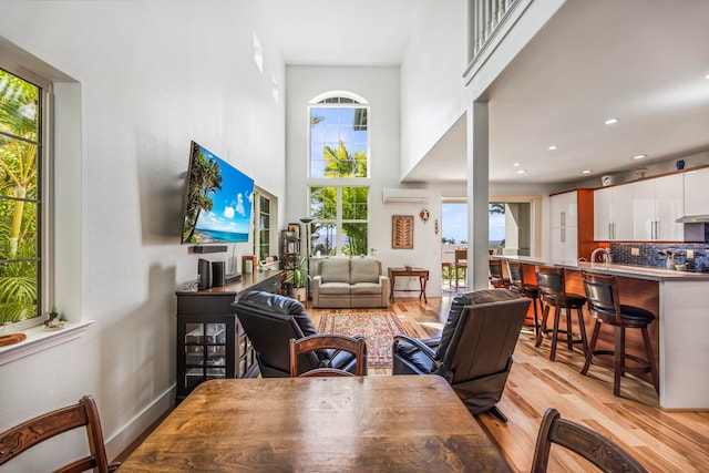 dining space featuring an AC wall unit, a wealth of natural light, and light wood-type flooring