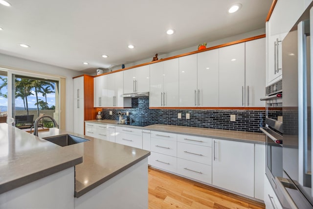 kitchen with white cabinetry, sink, light hardwood / wood-style floors, and black electric stovetop