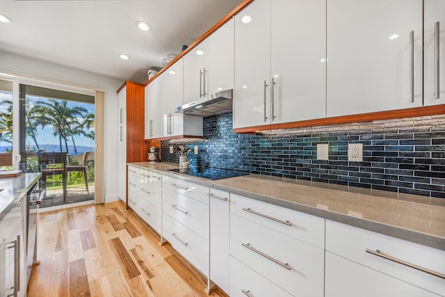 kitchen featuring tasteful backsplash, light stone counters, light hardwood / wood-style flooring, dishwasher, and white cabinets