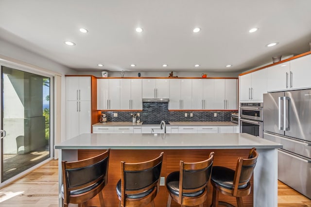 kitchen with white cabinets, stainless steel appliances, and a kitchen island with sink