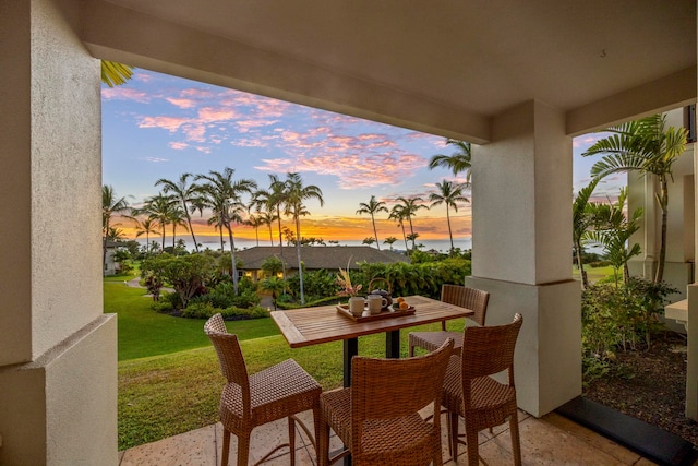 patio terrace at dusk featuring a lawn