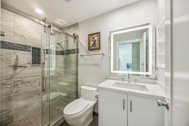 bathroom featuring vanity, a shower with shower door, and toilet