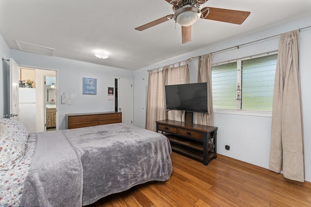 bedroom featuring ceiling fan, white refrigerator, light hardwood / wood-style flooring, and ensuite bath