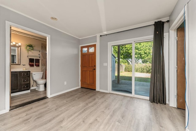 foyer entrance with crown molding and light hardwood / wood-style flooring