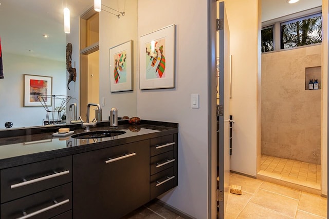 bathroom with vanity, a tile shower, and tile patterned flooring