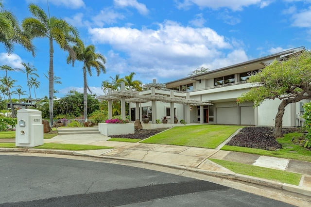 view of front of property with a balcony, a pergola, and a front lawn