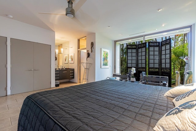 bedroom featuring ceiling fan, a wall of windows, ensuite bathroom, and light tile patterned floors