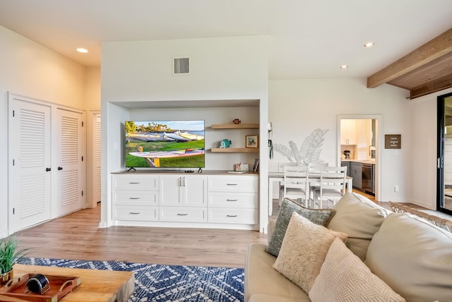 living room featuring light wood-type flooring and vaulted ceiling with beams