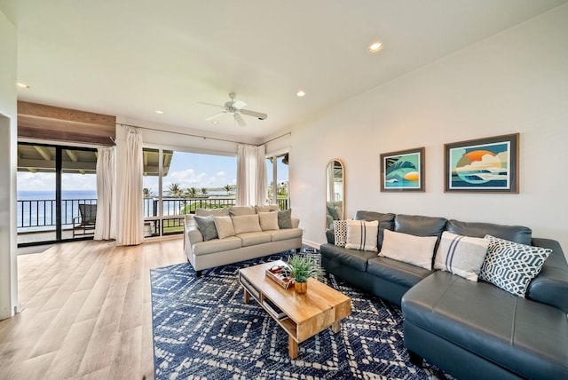 living room with light wood-type flooring, ceiling fan, and a water view