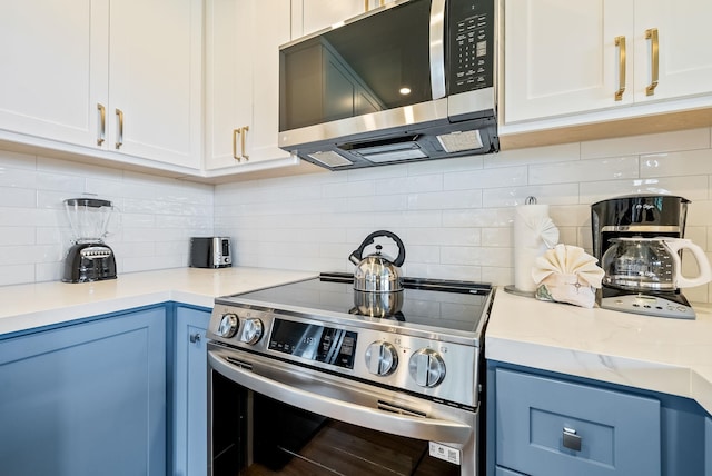 kitchen featuring tasteful backsplash, light stone countertops, white cabinets, and stainless steel appliances