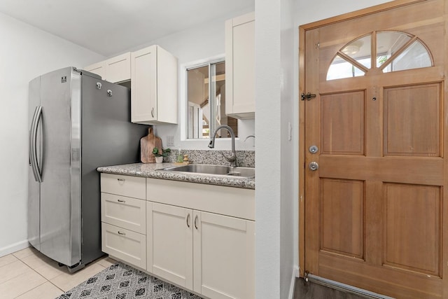kitchen featuring a sink, freestanding refrigerator, white cabinets, and healthy amount of natural light