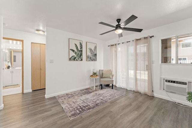 living area with wood finished floors, ceiling fan, cooling unit, and baseboards