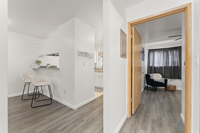corridor featuring light wood-type flooring and baseboards