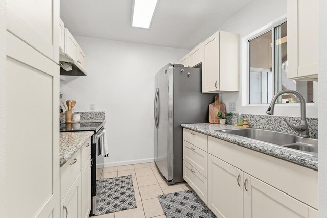 kitchen with a sink, under cabinet range hood, stainless steel appliances, light countertops, and light tile patterned floors