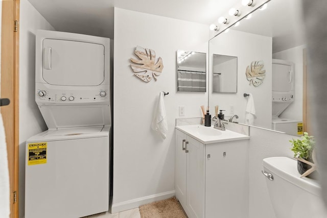bathroom with stacked washer / drying machine, toilet, vanity, and baseboards