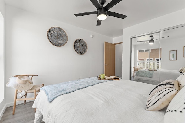 bedroom featuring light wood finished floors, baseboards, ceiling fan, and a closet