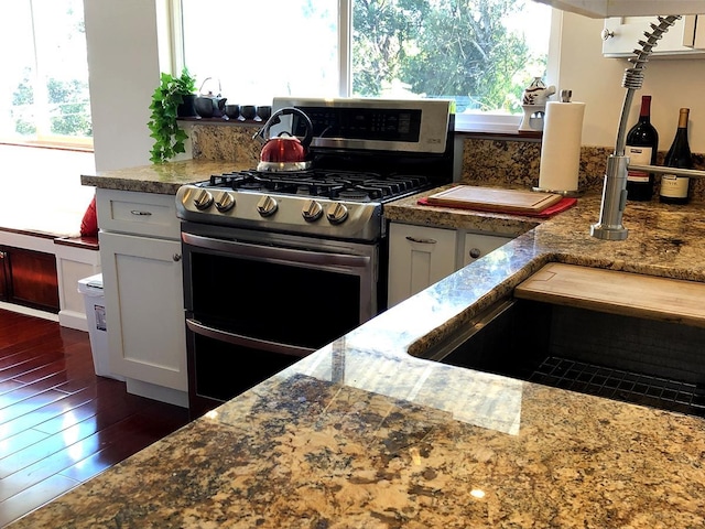 kitchen with white cabinetry, dark hardwood / wood-style flooring, and range with two ovens