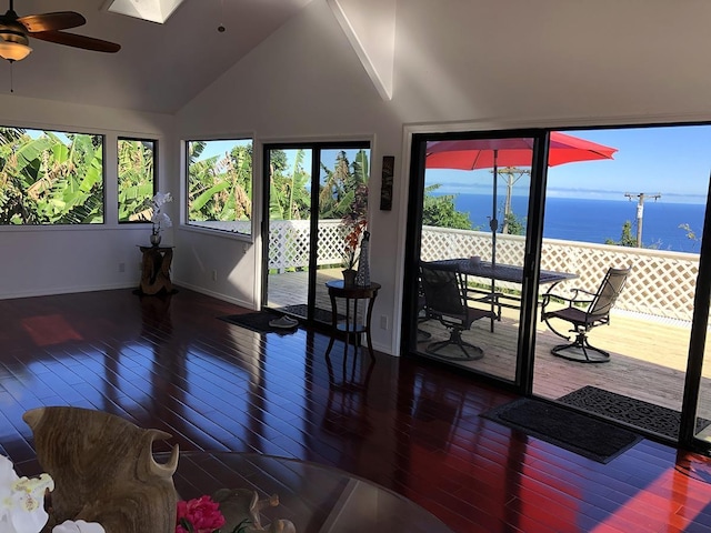 living room with wood-type flooring, a water view, vaulted ceiling with skylight, and ceiling fan