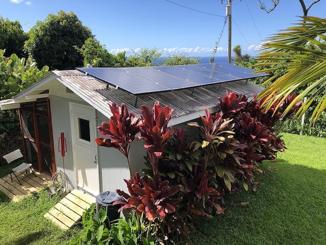 rear view of property featuring a yard and solar panels