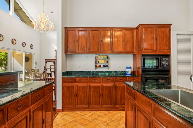 kitchen with a high ceiling, an inviting chandelier, dark stone counters, light tile patterned flooring, and black appliances