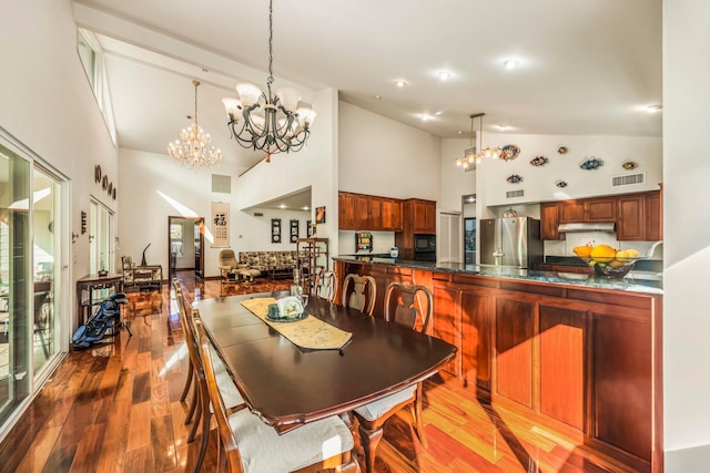 dining space featuring a chandelier, hardwood / wood-style flooring, and high vaulted ceiling