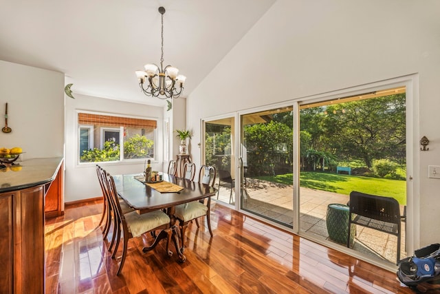 dining room with hardwood / wood-style floors, high vaulted ceiling, a wealth of natural light, and a chandelier