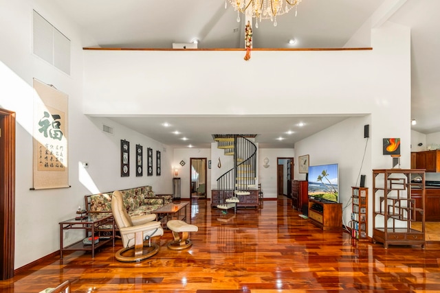 living room featuring wood-type flooring, an inviting chandelier, and a high ceiling