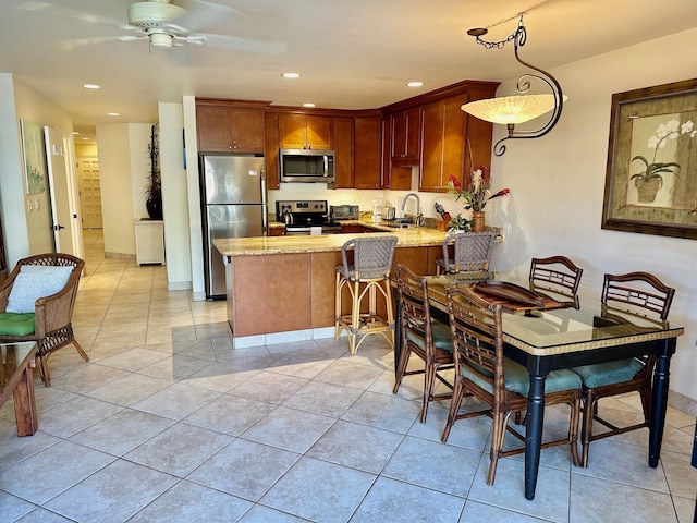 kitchen with ceiling fan, sink, hanging light fixtures, stainless steel appliances, and kitchen peninsula