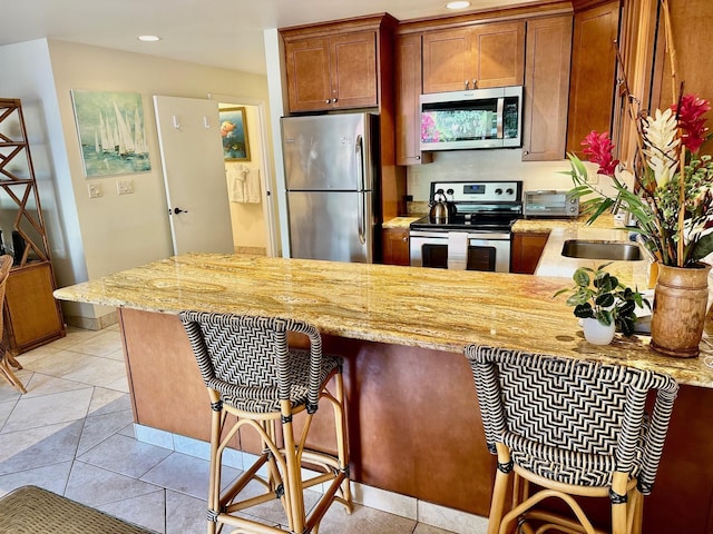 kitchen featuring kitchen peninsula, a kitchen breakfast bar, stainless steel appliances, and light tile patterned floors