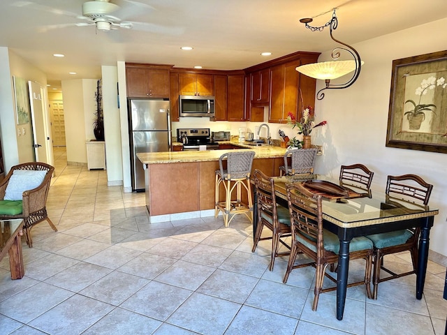 kitchen featuring ceiling fan, sink, stainless steel appliances, kitchen peninsula, and pendant lighting