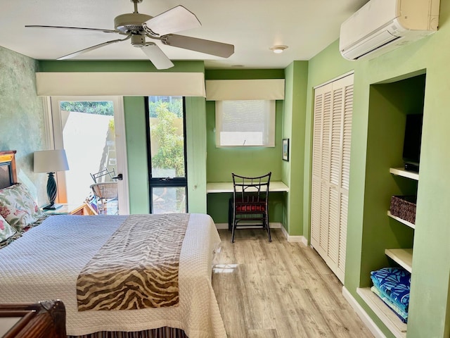 bedroom with a wall mounted air conditioner, light hardwood / wood-style flooring, a closet, and ceiling fan