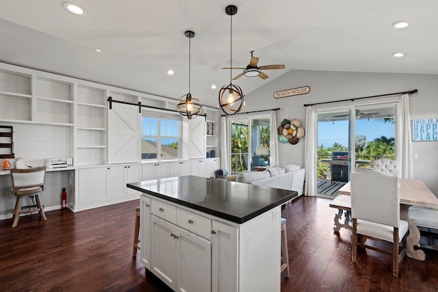 kitchen with hanging light fixtures, a barn door, dark countertops, and white cabinetry