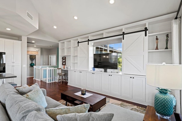 living area with a barn door, vaulted ceiling, dark wood finished floors, and recessed lighting