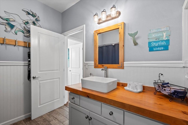 full bathroom with a wainscoted wall, curtained shower, wood finished floors, and vanity