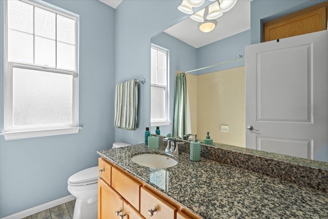 full bath with toilet, vanity, a wealth of natural light, and baseboards