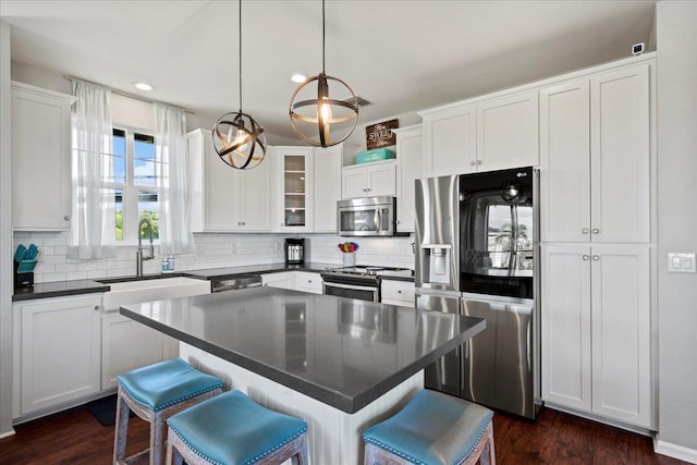 kitchen with dark countertops, white cabinetry, stainless steel appliances, and a center island