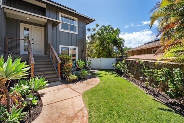 property entrance with a lawn, fence, and board and batten siding