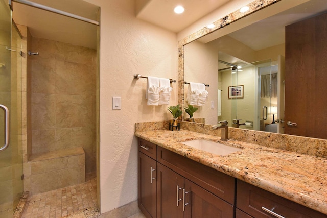 bathroom with vanity with extensive cabinet space and tiled shower