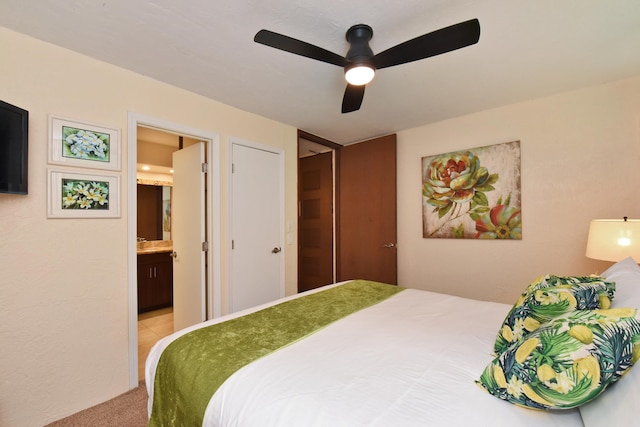 carpeted bedroom with a closet, ceiling fan, and ensuite bath