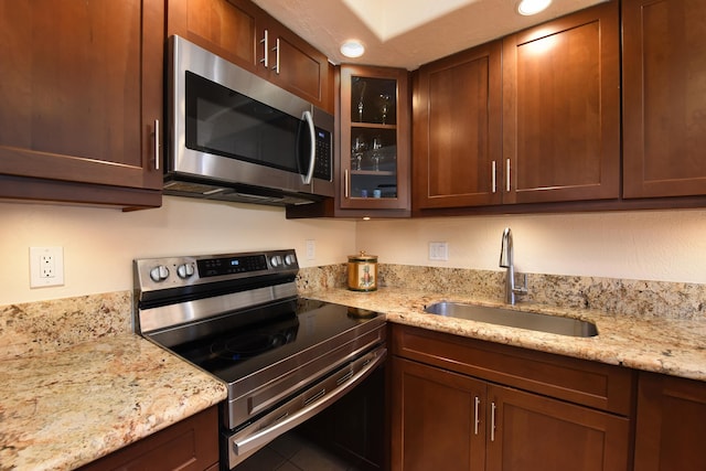 kitchen with tile floors, stainless steel appliances, sink, and light stone countertops